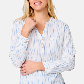 A woman smiles wearing the Clearance Women's Easy Breezy Long Sleeve Shirt, featuring a cotton-linen blend, light blue vertical pattern, buttoned neckline and cuffs. She crosses her left arm while her right fist rests near her chin.