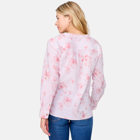 A woman with blonde hair stands facing away against a light gray background, wearing the Clearance Women's Easy Breezy Long Sleeve Shirt in a light pink floral cotton-linen blend top and blue jeans.