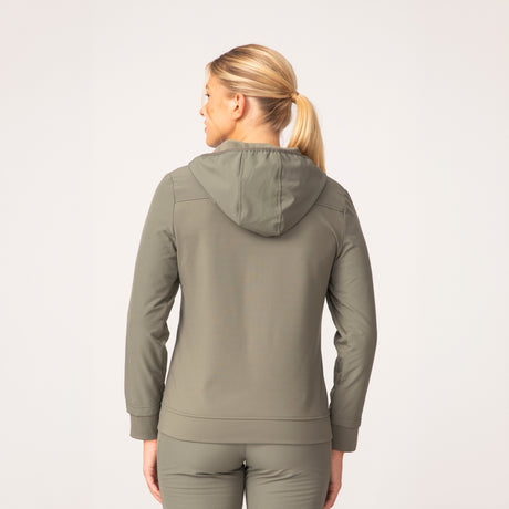 [London is 5'9.5" wearing a size Small.] Woman wearing Free Country Women's Venture Out Hybrid Jacket in black with a full front zipper opening, lower pockets, stretch panels, a hood, and water resistant and wind resistant stretch performance fabric, light grey background. Best women’s jacket for all weather.