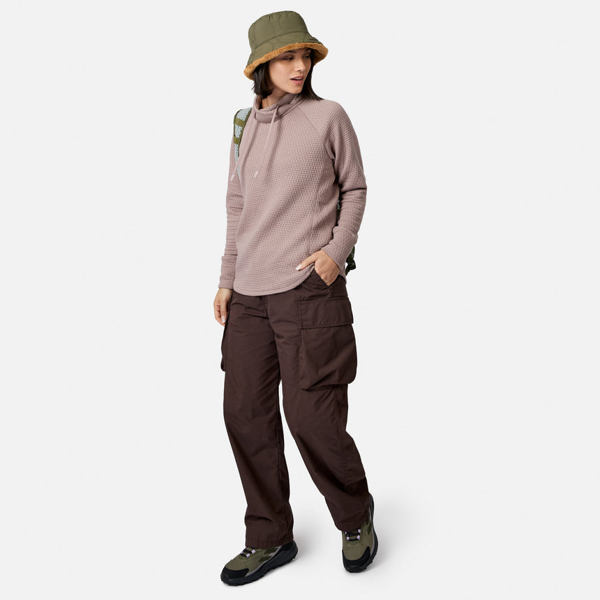 Person wearing a textured mauve Women’s UltraFill Cowl Neck Top, dark brown cargo pants, an olive green bucket hat, and hiking sneakers.