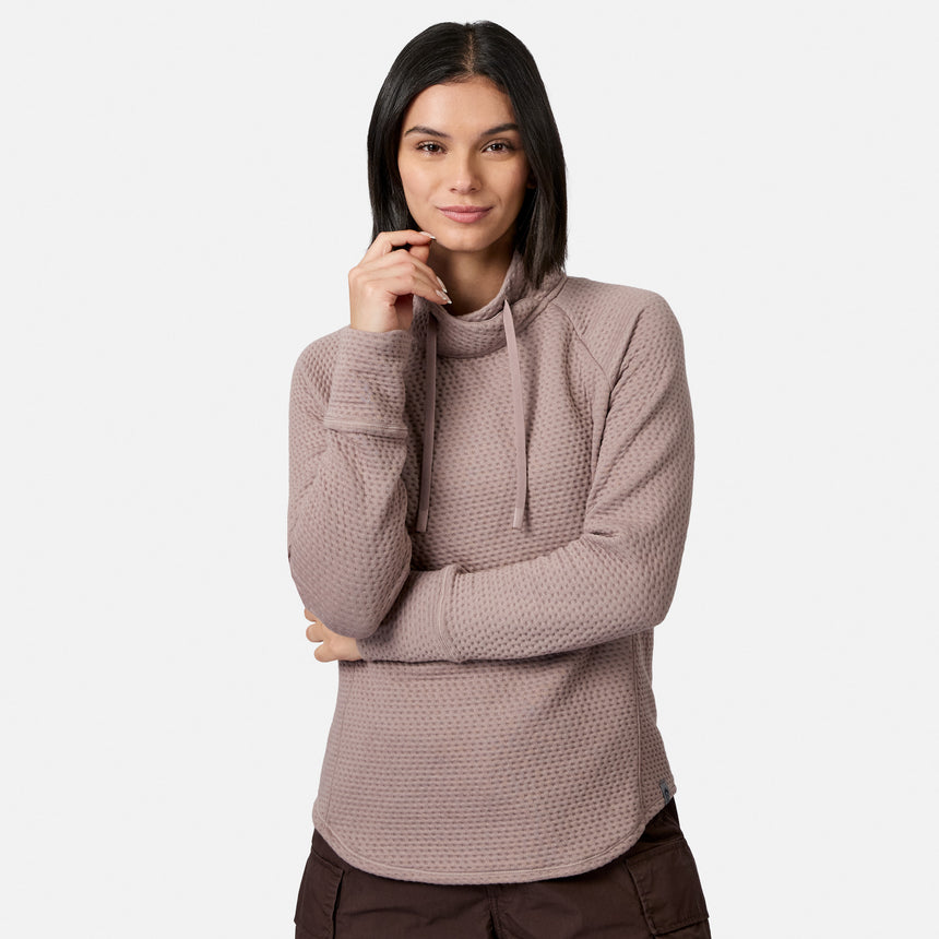 A woman wears a fawn Free Country Women’s UltraFill Cowl Neck Top featuring seamless quilting, a cowl neck collar, and drawstrings.