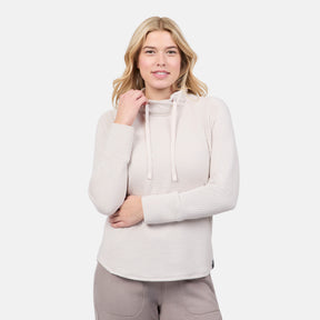 A woman smiles with one hand at her neck, modeling the Free Country Women's UltraFill Cowl Neck Top—featuring seamless quilting and light polyester fill—against a plain white background.