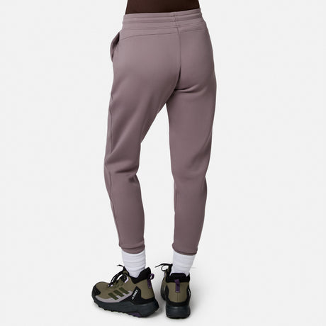 Model wearing Free Country Women’s Sueded Lush Jogger in mauve with white socks and green-black sneakers, shown from the back against a plain white background.