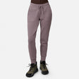 Model wears Free Country Women’s Sueded Lush Jogger in Zinc, featuring 4-way stretch, front pockets, and drawstring waist, paired with olive green and black hiking shoes. White background.