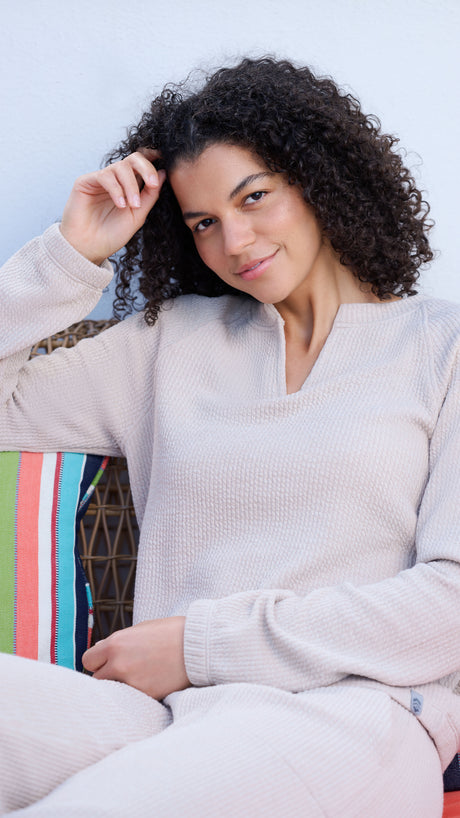 Woman sitting on a colorful chair wearing a light gray sweater.