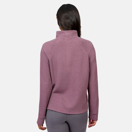 A person faces away, wearing the Free Country Women’s Ripple Knit Half Zip Top in mauve with gray pants against a plain white background—ideal for casual layering.