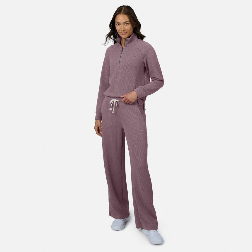A woman stands confidently, smiling in Free Country Women’s Ripple Knit Long Wide Leg Pant and a matching top with white sneakers, her long hair flowing gracefully against a plain white background.