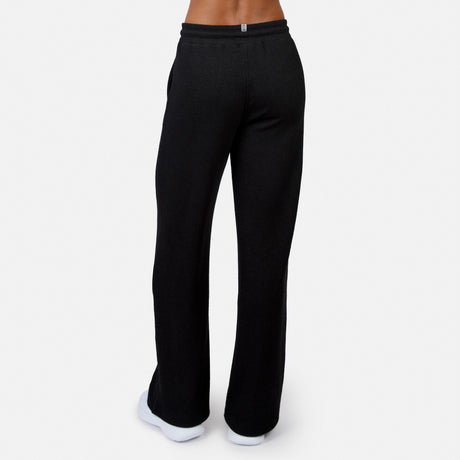 A person wearing Free Country Women’s Ripple Knit Long Wide Leg Pant in black with white sneakers, photographed from the back against a plain white background.