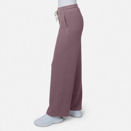 Side view of a person in Free Country Women’s Ripple Knit Long Wide Leg Pant with pockets, styled with white sneakers, standing against a plain white background.