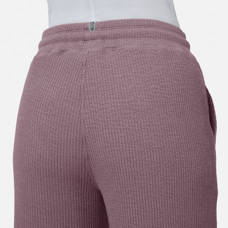 Close-up of a person wearing Free Country’s Women’s Ripple Knit Long Wide Leg Pant in mauve, paired with a white top. The image highlights the textured waistband and upper legs of these breathable pants against a plain background.