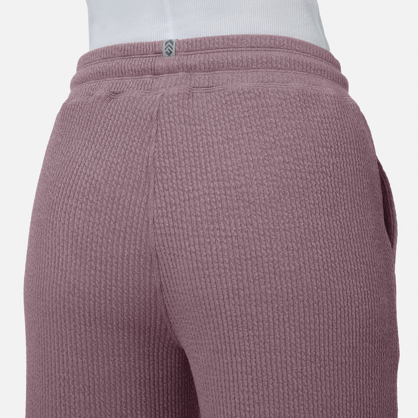 Close-up of a person wearing Free Country’s Women’s Ripple Knit Long Wide Leg Pant in mauve, paired with a white top. The image highlights the textured waistband and upper legs of these breathable pants against a plain background.