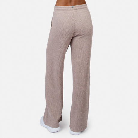 A person wearing Free Country Women’s Ripple Knit Long Wide Leg Pant in beige ribbed knit with white sneakers, shown from the back against a plain white background.