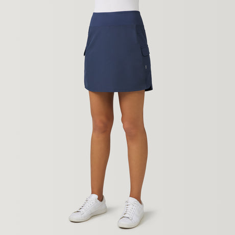 Navy blue moisture-wicking Women’s Free 2 Explore Hybrid Skort with side pockets, worn with a white shirt and white sneakers.