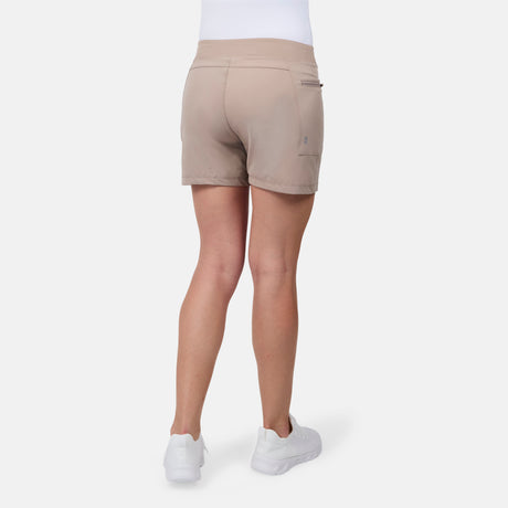A person is shown from the back against a plain white background, wearing the Free Country Women's Trail to Town Short in beige with white sneakers.