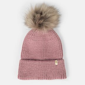 The Women's Rib Knit Cuffed Beanie with Pom by Clearance is a pink winter hat featuring a rib knit design, a folded brim, and a large faux fur pom-pom on top, shown against a white background.