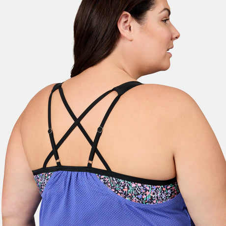 [Melissa is 5'10" wearing size 1X] Woman wearing a blue sports bra with floral trim and criss-cross straps on a white background