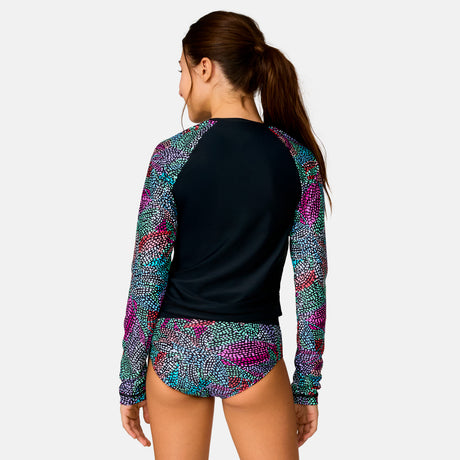 [Model is wearing a size Medium.] Girl wearing the Free Country Girls' Fresco Rash Guard and Bikini Swim Set in Black Fresco, size M, featuring a raglan sleeve rash guard and racerback tankini top and lined bikini bottom made from recycled polyester fabric that provides four way stretch and upf protection #color_ Black-Fresco