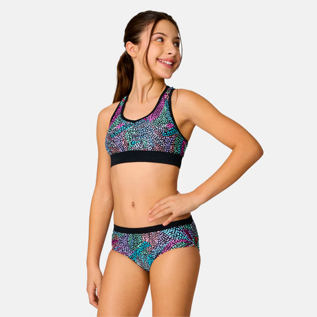 [Model is wearing a size Medium.] Girl wearing the Free Country Girls' Fresco Rash Guard and Bikini Swim Set in Black Fresco, size M, featuring a raglan sleeve rash guard and racerback tankini top and lined bikini bottom made from recycled polyester fabric that provides four way stretch and upf protection #color_ Black-Fresco