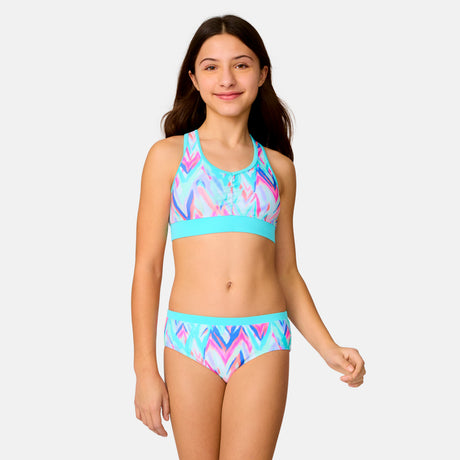[Model is wearing a size Medium.] Girl wearing the Free Country Girls' Fresco Rash Guard and Bikini Swim Set in Aquatopia Oasis Chevron, size M, featuring a raglan sleeve rash guard and racerback tankini top and lined bikini bottom made from recycled polyester fabric that provides four way stretch and upf protection #color_ Aquatopia-Oasis-Chevron