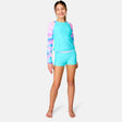 [Model is wearing a size Medium.] Girl  wearing the Free Country Girls' Dreamy Drift Rash Guard Swim Set in Aquatopia Dreamy Drift, size M, featuring a raglan sleeve rashguard and boy shorts made from recycled polyester fabric that provides four way stretch and upf protection #color_ Aquatopia-Dreamy-Drift