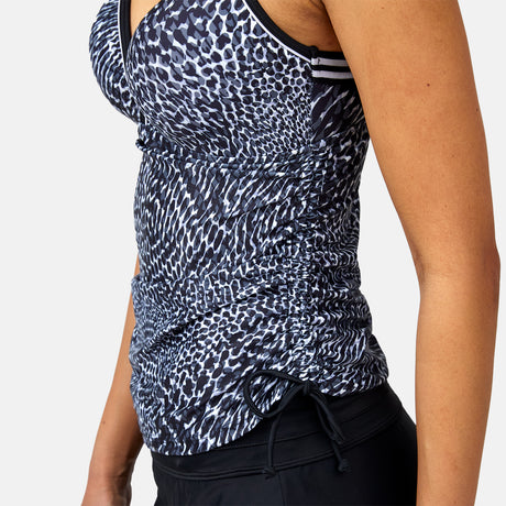 Model wears the Women's Sea Skin Track Stripe Tankini by Clearance—sleeveless, fitted, side ruching, wireless molded cups—with black athletic bottoms; shown from shoulders to hip against a plain background.