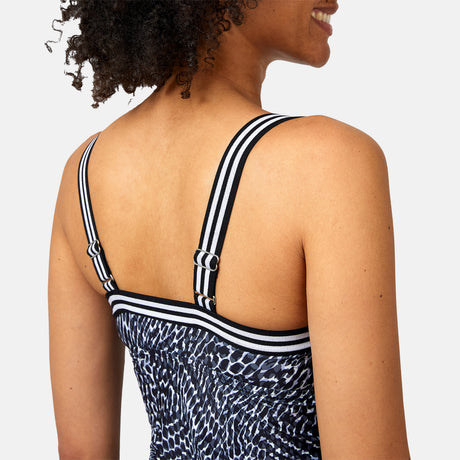 A woman smiles, seen from the back and side, wearing the Clearance Women's Sea Skin Track Stripe Tankini—a sleeveless top with black and white animal print, wireless molded cups, and thick, striped adjustable elastic straps.