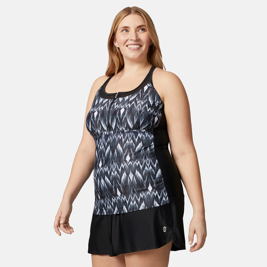 A woman with long, light brown hair models the Clearance Women's Plus Size Tango Mesh Zip Up Racerback Tankini Top—a black and white quick-drying swim top—paired with a black swim skirt, smiling against a plain white background.