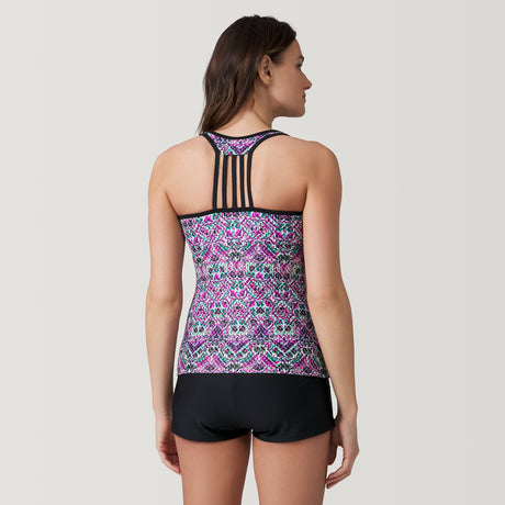 A woman faces away, wearing the Clearance Women's Mosaic Mirage Lace Up Racerback Tankini Top with purple, pink, and blue mosaic prints, black multi-strap racerback details, UPF 50+ protection, and black shorts. Background is light gray.