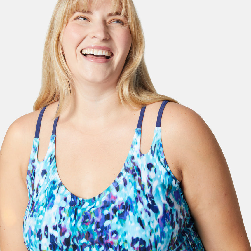 [Lola is 5'10" wearing size 1X] Woman wearing a colorful swimsuit with blue straps against a white background