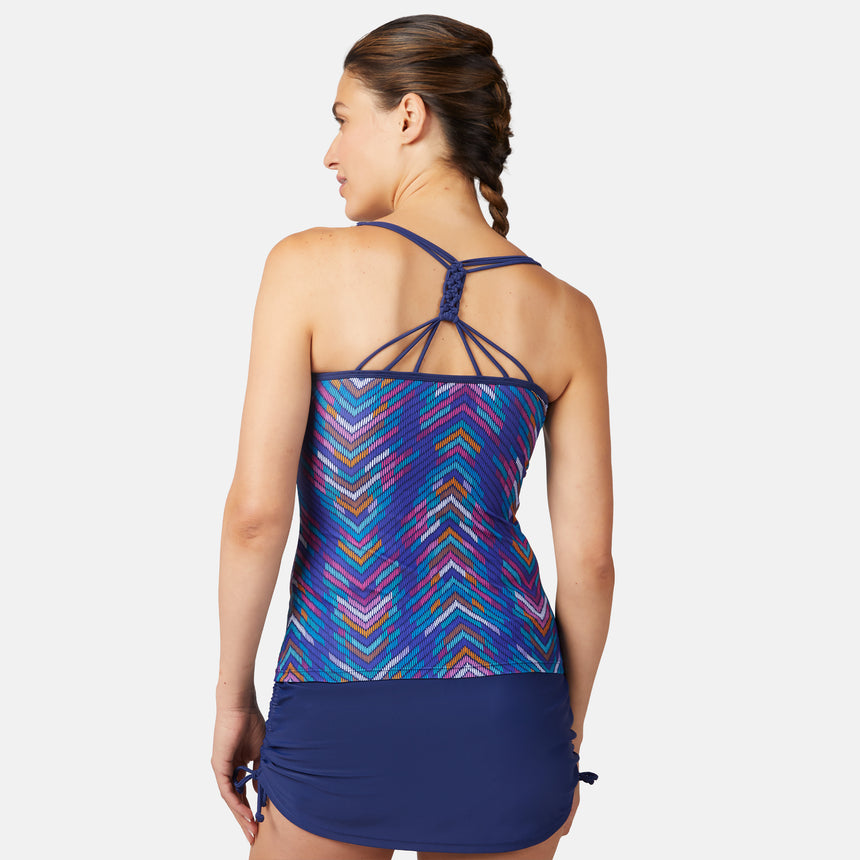 [Olga is 5'10" wearing size S.] Woman wearing a colorful blue tankini top with a geometric pattern and navy blue skirt on a white background