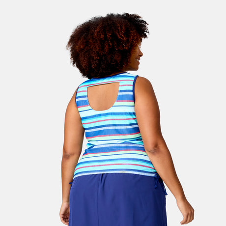 A woman with curly hair is shown from the back, wearing the Women's Plus Size Marina Stripe Full Side Shirring Tankini Top by Clearance, featuring blue, teal, and white stripes and a square upper back cutout, paired with a blue skirt.