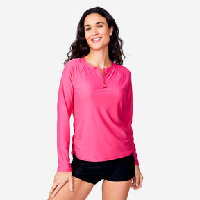 A woman with long dark hair smiles in a Clearance Women's Long Sleeve Zip Swim Shirt with Built-in Bra, UPF 50+, paired with black shorts against a plain light background.