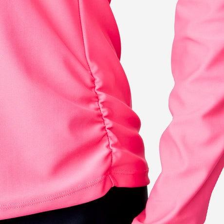 Close-up of a person wearing the Women's Long Sleeve Zip Swim Shirt with Built-in Bra by Clearance in bright pink, featuring side ruching, crafted from recycled poly-spandex, paired with black pants against a plain white background.