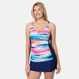 [London is 5'9.5" wearing size S] Woman wearing a colorful tankini top and navy skirt on a white background
