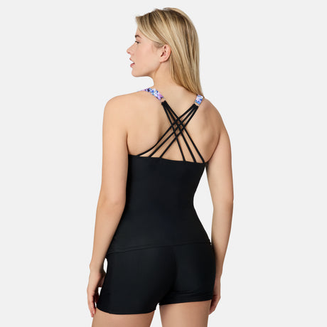 [Olga is 5'10" wearing size S.] Woman wearing a colorful periwinkle tankini top with black criss cross back and black shorts on a white background