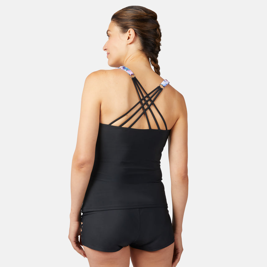 [Olga is 5'10" wearing size S.] Woman wearing a colorful periwinkle tankini top with black criss cross back and black shorts on a white background