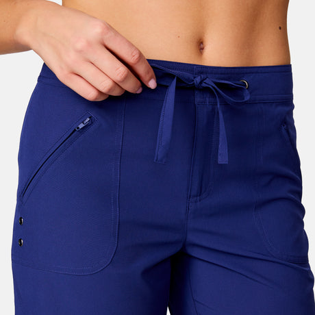 [Model is wearing a size Small.] Woman wearing Free Country Women's 7" Bermuda Board Short in Marine, size S, made from quick drying UPF stretch performance fabric featuring a fly front zipper closure with a drawcord and two front pockets 