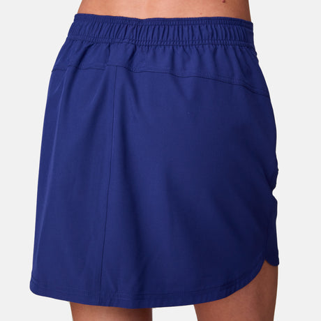 A close-up of a woman wearing the Free Country Women's Beach and Beyond Skort, showcasing its blue color, elastic waistband, and four-way stretch, viewed from the back against a plain white background.
