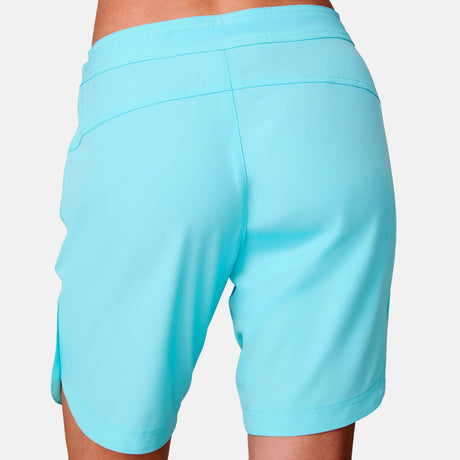 A close-up rear view of a person wearing the Women's Bermuda Board Short II in light blue, shown from waist to above the knees, set against a plain white background.