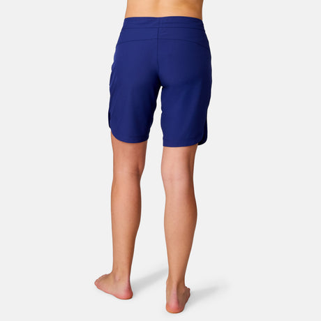 A person standing barefoot on a white background, shown from the waist down, is wearing the Women's Bermuda Board Short II in navy blue, featuring a relaxed fit and quick-drying fabric.