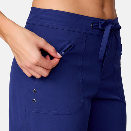 [Model is wearing a size Small.] Woman wearing Free Country Women's 5" Bermuda Board Short in Marine, size S, made from quick drying UPF stretch performance fabric featuring a fly front zipper closure with a drawcord and two front pockets 