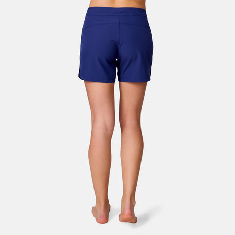 [Model is wearing a size Small.] Woman wearing Free Country Women's 5" Bermuda Board Short in Marine, size S, made from quick drying UPF stretch performance fabric featuring a fly front zipper closure with a drawcord and two front pockets 