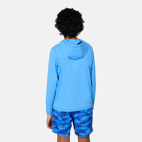 A child with curly hair is shown from the back, wearing the Free Country Kids' Everybody SunFree UPF Hoodie in light blue and shark-patterned blue swim shorts, standing against a plain white background.