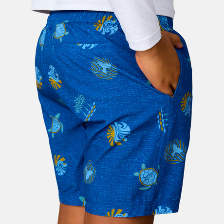 [Model is wearing a size Medium.] Boy wearing the Free Country Boys' Sunset Voyage Swim Short in Blue Sunset Voyage, size M, featuring recycled polyester fabric and elastic waistband and upf protection, paired with white sunshirt #color_ Blue-Sunset-Voyage
