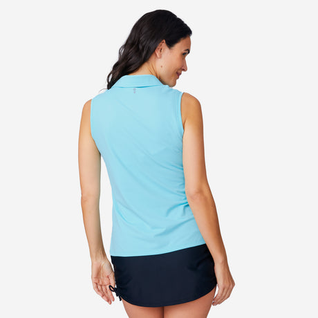 A woman with long dark hair is shown from the back, wearing the Free Country Women's SunFree Sleeveless Top in light blue and a short black skirt against a plain white background.