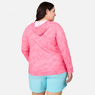 A woman is seen from the back wearing the Free Country Women's Plus Size SunFree UPF Hoodie, which features a pink floral pattern and moisture-wicking technology, paired with light blue shorts. The hoodie offers UPF 50+ sun protection, providing both style and functionality against a plain white background.