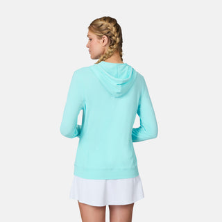A woman with blonde braids faces away, wearing the Free Country Women's SunFree UPF Hoodie in light blue and a white skirt, set against a plain white background.