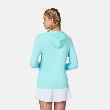 A woman with blonde braids faces away, wearing the Free Country Women's SunFree UPF Hoodie in light blue and a white skirt, set against a plain white background.