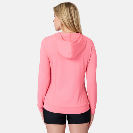 A woman with blonde hair wears the Free Country Women's SunFree UPF Hoodie in bright pink and black shorts, standing with her back to the camera against a plain white background.