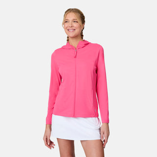 A woman smiles with her hands relaxed at her sides, modeling the Free Country Women's SunFree Full Zip UPF Sunshirt in bright pink and a white tennis skirt against a plain light background.